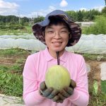 自社農園で育てたメロンを持つ社員